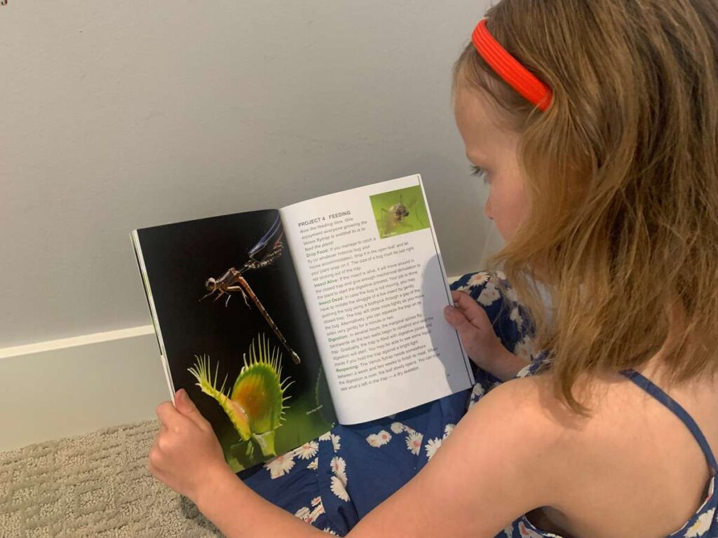 image of a girl leaning about STEM with a venus fly trap book for kids